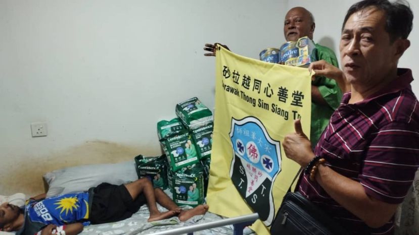 砂同心善堂执行秘书陈惠生将布施品移交不幸卧床的印度裔青年父亲。