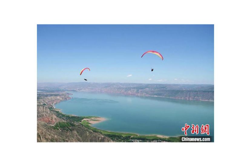 滑翔伞运动员在甘肃刘家峡水库上空竞技。