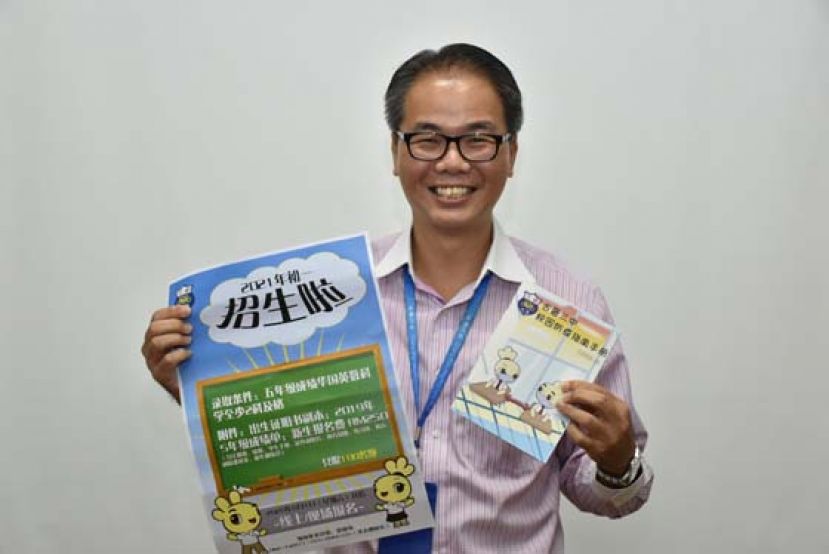 古晋三中校长李志鹏展示2021招生海报及校园防疫指南手册。