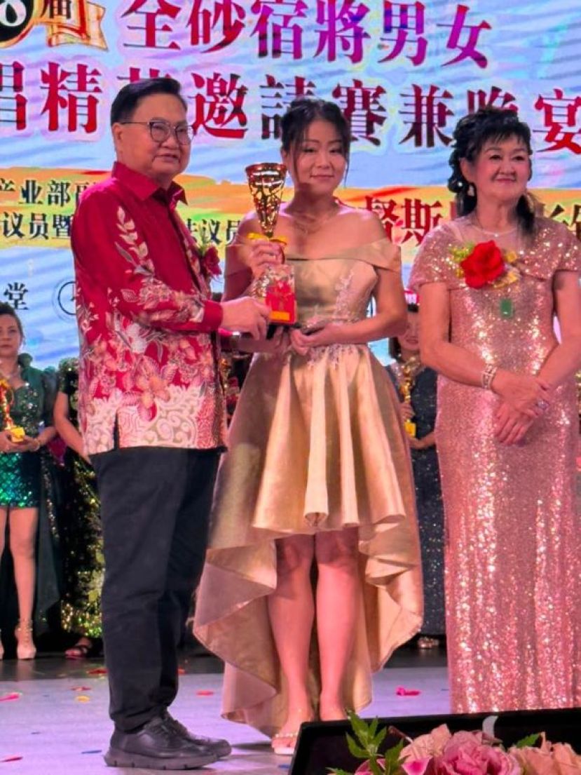 古晋艺星歌手刘于萍（中）自斯木省华总会长拿督吴标生博士（左）手中领取女子组冠军奖杯时。右为泗里街佳佳歌唱文娱社社长兼筹备会主席俞燕希。