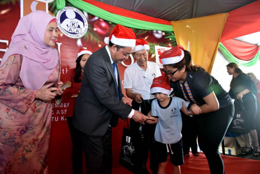 砂经济发展局主席丹斯里拿督阿玛阿都阿兹（左二）派发圣诞礼物予古晋自闭症协会的孩子。