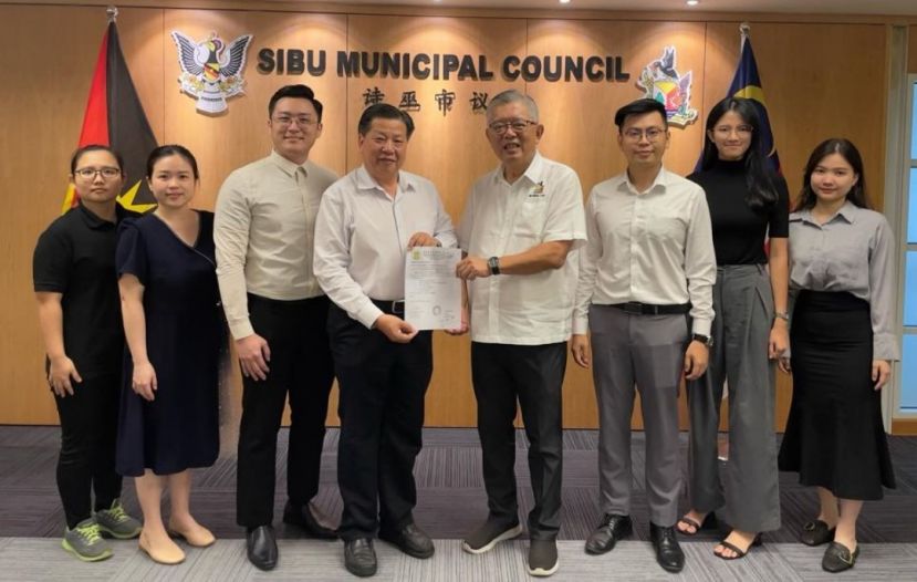 砂医总会长江宗兴（左4）联袂理事移交同福建中医药大学签署合作备忘录见证邀请函予诗巫市议会主席丁永豪；左起为林可妮、黄如君、黄思鸣；右起是林雅婷、许傛傛、江邦发。