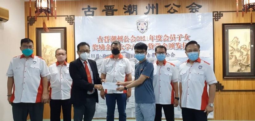 颁发会员子女学业优良奖励金活动进行时影。在会长周文盛（中）与执委见证下，由该会公关主任拿督沈坚石（左三）颁发奖励金予一得奖者。右一及二分别是该会第二副会长陈瑞光和秘书长林苇。左二为财政林瑞钊和产业主任卢少奎（左一）。
