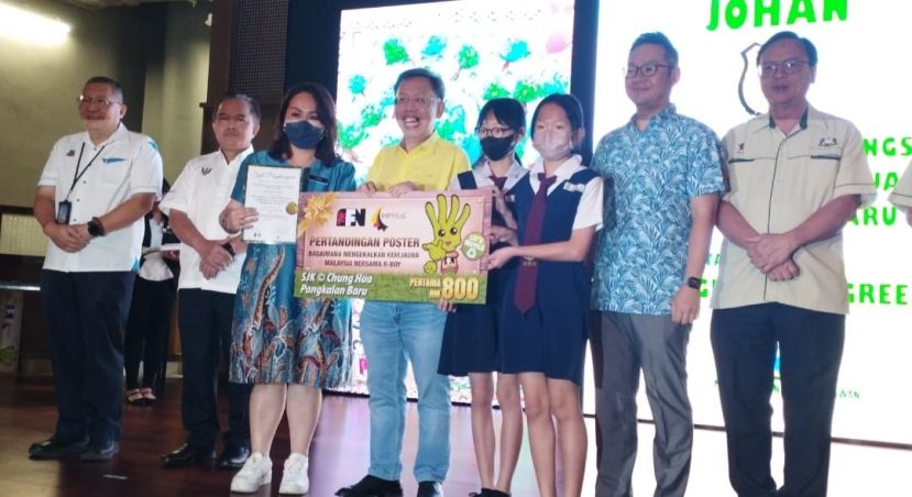荣获海报设计比赛，小学组冠军的新梯头中公的师生，从砂副总理拿督斯里沈桂贤手中接过模拟支票和奖状时摄。