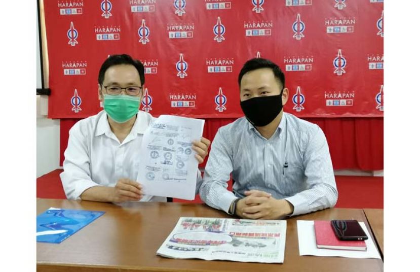 砂行动党主席张健仁（左）展示7哩益安城商家们联名签署的信函时摄，右为其特别助理江峰年。