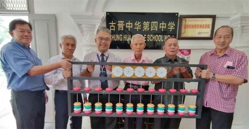 官晨阳校长（左3）接收由方由传（左4）赠予四中的方氏数字转轮算盘大型模型；左起为陈中兴、校董何健赞；右是孙守生、甲必丹林传政。