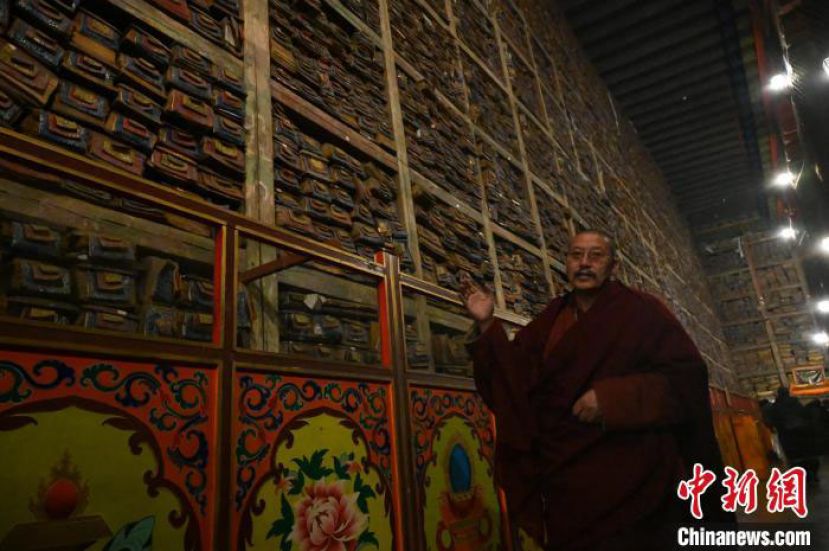 在萨迦寺经书墙下，洛卓土美介绍古籍经书数字化情况。