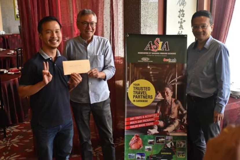 砂境内旅行社协会主席杨启良（中）颁发巨奖优胜者甄洪生（左）他获得双人古晋来回姆禄机票与2天1夜在姆禄度假屋旅游配套，右一为秘书蔡润铨。