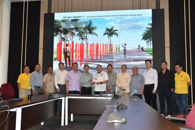 古晋中华总商会会长陈日枝(左六)移交捐款给予古晋南市市长黄鸿圣(左七)。左起为古晋南市市议员郑神彬、古晋中华总商会工业组副主任杨惠升、古晋中华总商会福利组主任朱昌亮、古晋中华总商会副秘书长许瑞益、古晋中华总商会密秘书长拿督蔡文铎；右起古晋南市市议员郑志国、古晋中华总商会公关组副主任本曼查陈君义、古晋中华总商会财政何修华、古晋中华总商会副会长范庆和、砂拉越文化研究学会会长拿督邓伦奇及古晋南市副市长拿督再迪苏海里。