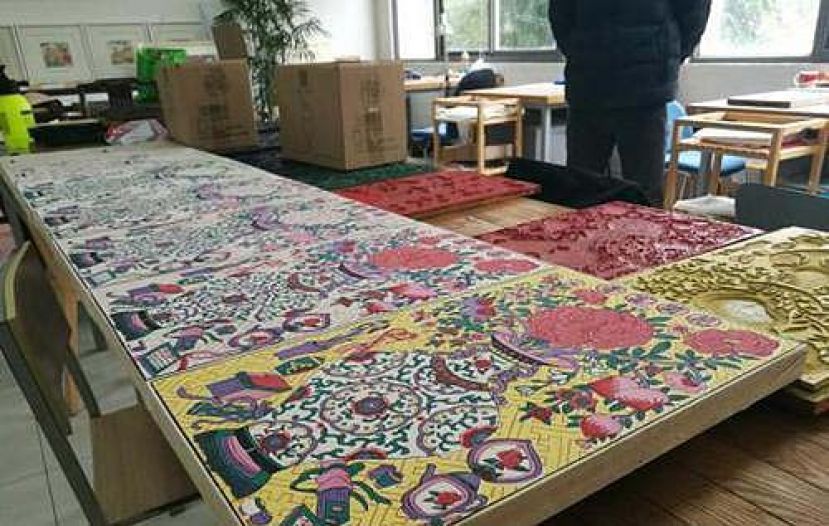 图示：五颜六色的年画雕版铺满了桌子。
