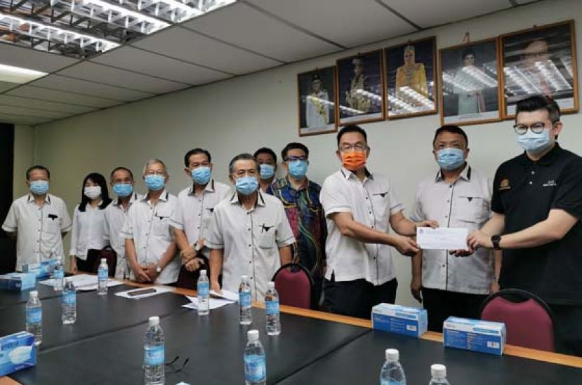 古晋区国会议员俞利文（右1）在晋汉连省华小董联会会长蔡文铎（右2）等人见证下移交捐款予田松茂。