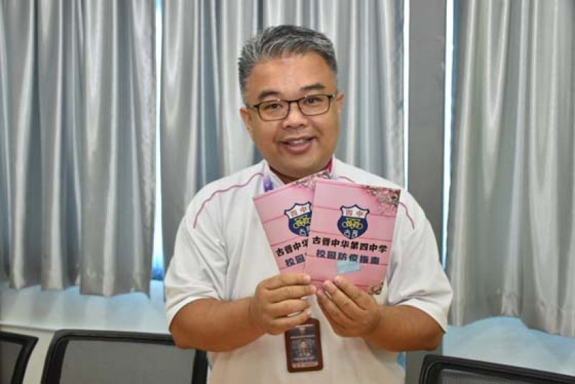 四中校长官晨阳展示校园防疫指南。