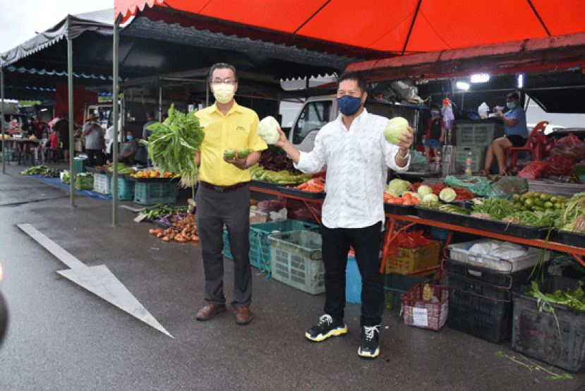 人联党圣淘沙支部主席叶耀星及Aeroville Mall 董事甲必丹陈君义展示蔬菜批发市场的蔬菜。