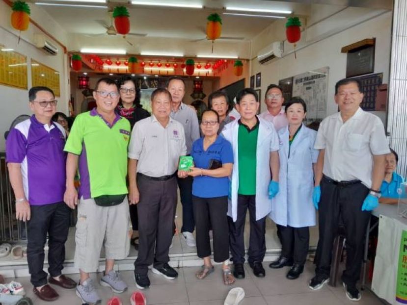 官锦镇阁长（左3）派&ldquo;脱苦宝消炎镇痛风湿膏&rdquo;予义诊有需要人士。左起为义诊筹委主席拿督李奇生、温燕清阁长，右起是陈中兴，龚桂蓉、许国模。
