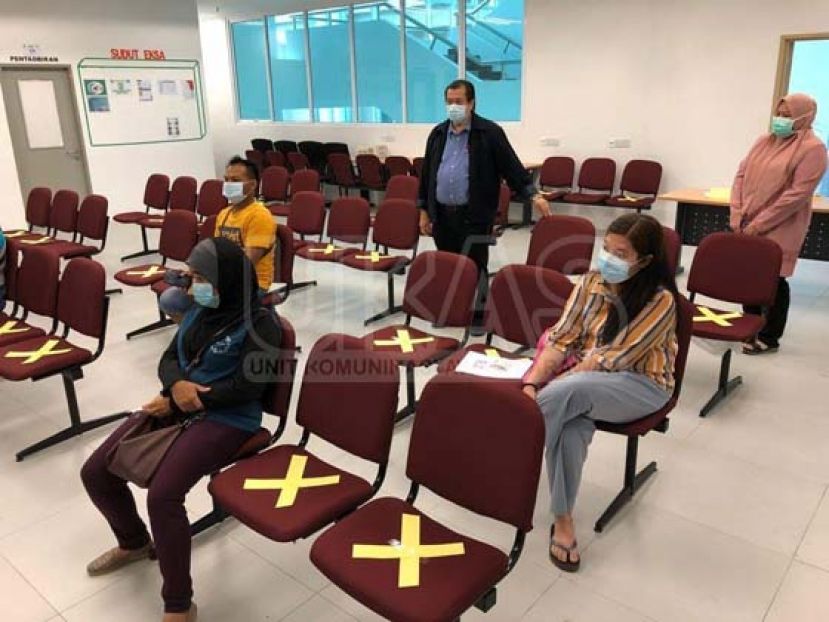 阿都阿兹（站者左）巡视一政府部门后，对该部门采取的社交距离感到满意。