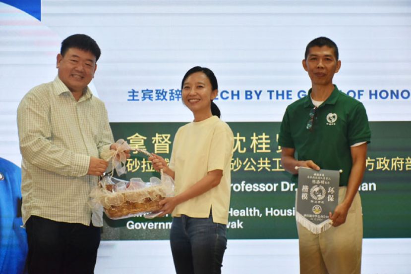 砂中总会长江昌文（左）赠送纪念品予砂副总理拿督阿玛沈桂贤的代表砂总理署政治秘书许德婉（中），右为&ldquo;如何留住蓝色的天空&rdquo;为主题的环保酵素公益工作坊讲师陈添明。