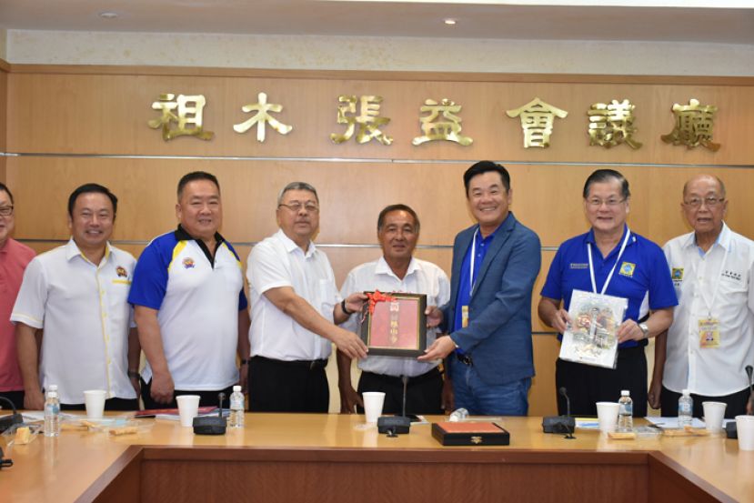 古晋福建公会监察主席兼砂诏安会馆主席许庆喜（左三）赠送纪念品予柔佛新山福建会馆拿督林德明（右三）。