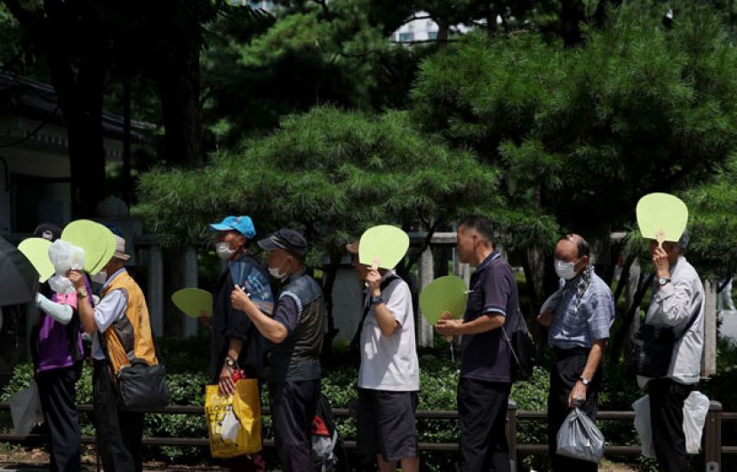 韩国首尔的老人顶著高温排队领取免费便当。