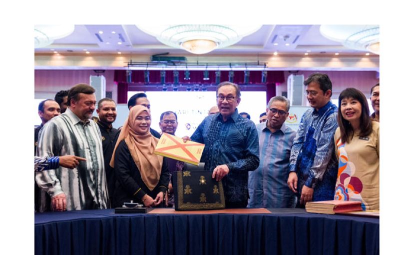 首相安华（中）在官员陪同下展示2025年财政预算案。