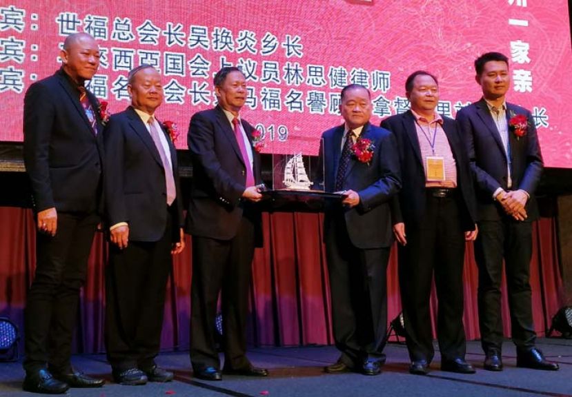 世福总会长吴换炎（左三）代表世福赠送象征一帆风顺的船支纪念品予大马福州社团联合总会，由马福总会长拿督斯里刘为强太平局绅（右三）接收。陪同在旁的为世福总会常务会长兼马福副会长拿督斯里王英顺（左)。