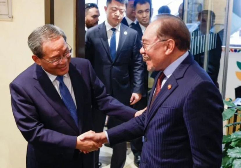 首相安华(右)与中国总理李强(左)亲切握手问好。