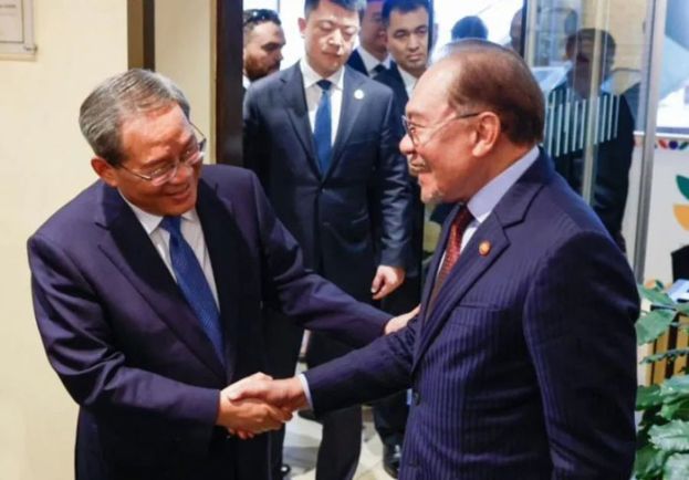 首相安华(右)与中国总理李强(左)亲切握手问好。