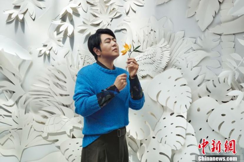 朝着两个方向盛开的并蒂花，一头是橙黄色，一头是墨绿色，花茎紧紧纠缠成一股，细细地拈在郎朗手中，这也是郎朗新专辑的封面。