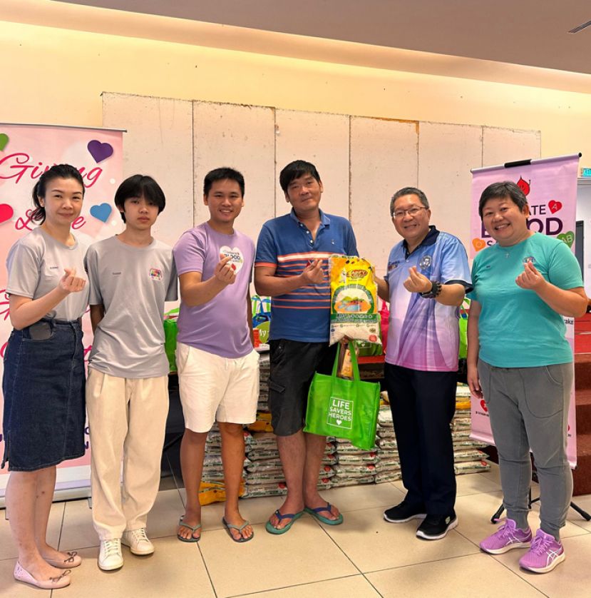 南市市长拿督黄鸿圣（右二）在古晋爱心书协会创办人兼主席吕晗韵（右一），秘书长田素瑛（左一）丶筹委主席吕立晟（左二）丶理事郑永祥（左三）的陪同下颁发礼包於捐血民众。