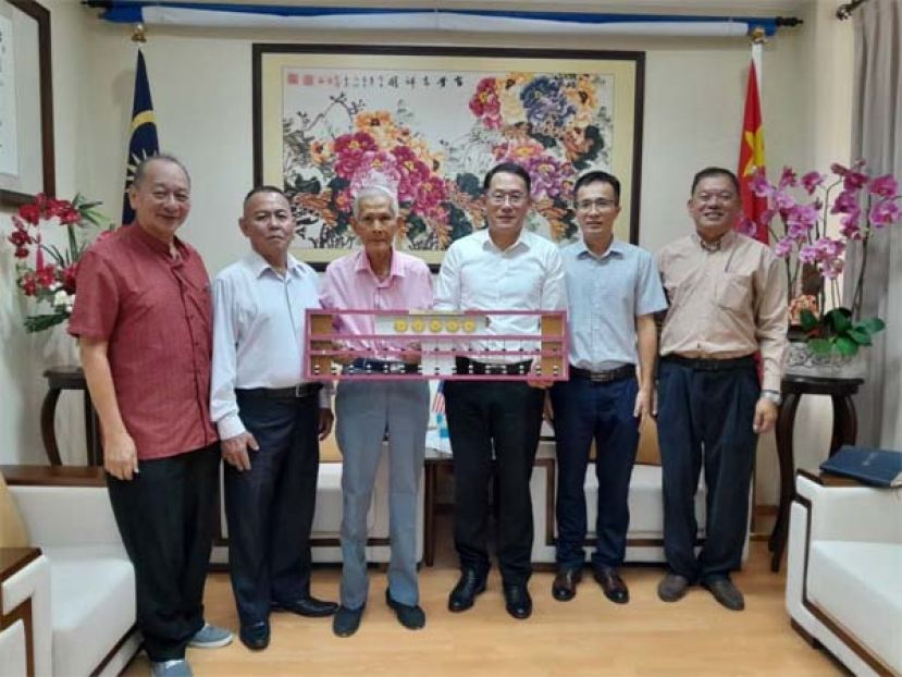 方由传（左3）赠其研发的&ldquo;方氏数字转轮算盘&rdquo;模型予邢伟平总领事。左起为孙守生、甲必丹林传政；右起是陈中兴、李炳炎副领事。