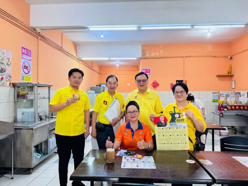 罗克强(站者右二)及团队派送日历给予十哩社区民众。站者左一为砂人联党十哩分部理事李欲熙及站者左二为巴达旺市議員林良紀及站者右一为团队团员詹美蘭。