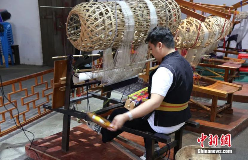 当地民众在使用传统织布机织壮锦。