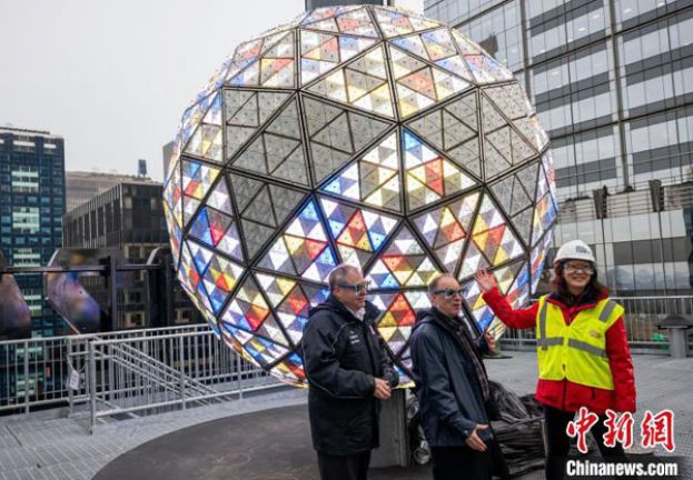 当地时间12月27日，纽约时报广场新年倒计时水晶球调试完毕后亮相。图为活动组织方之一、倒计时娱乐公司总裁杰弗里&middot;施特劳斯(中)和美中友好协会常务副会长李丽(右)在时报广场联盟负责人的见证下揭晓水晶球的全新灯光图案设计。