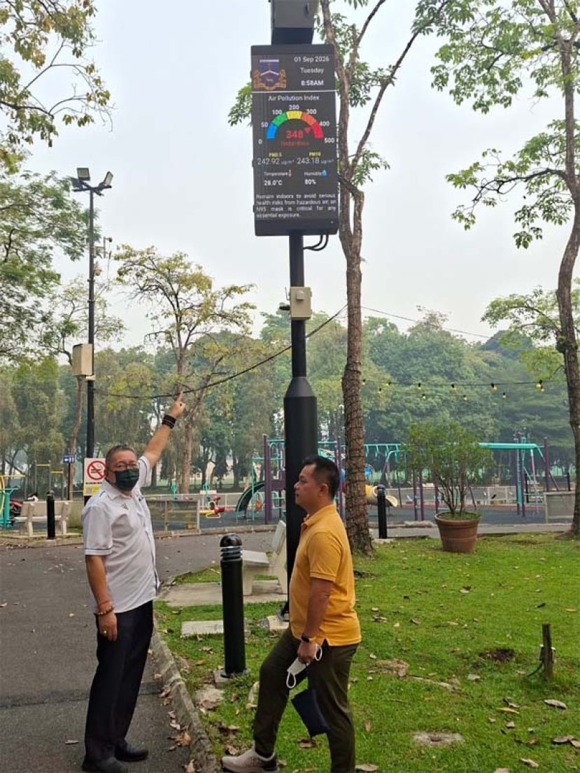 南市市长拿督黄鸿圣（左）查看智能杆显示系统，并说明有关空污指数与警示讯息出现不符的原因。右为市议员郑神彬。