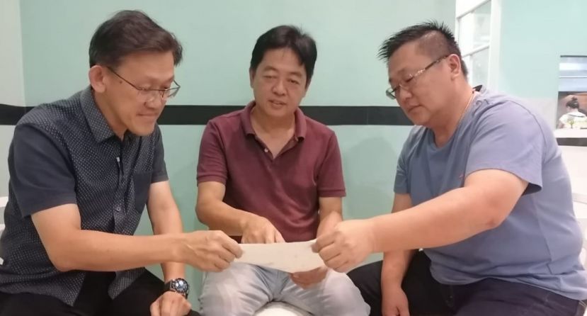    疑遭歹徒冒名向某银行申请信用卡盗提逾3万令吉事主许义华（中）在友人张荣华（右）陪同下，向砂人联党中央副主席薛华东（左）求助。