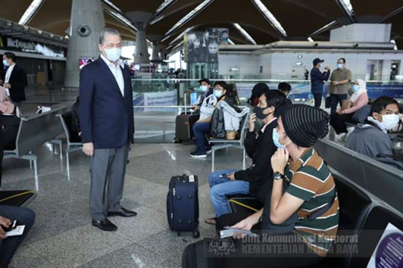 拿督斯里法迪拉（左）在吉隆坡国际机场与在砂执教的西马教师交流。