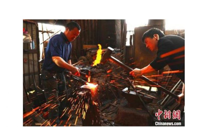 铁匠王岳平与王敏剑父子在打铁。