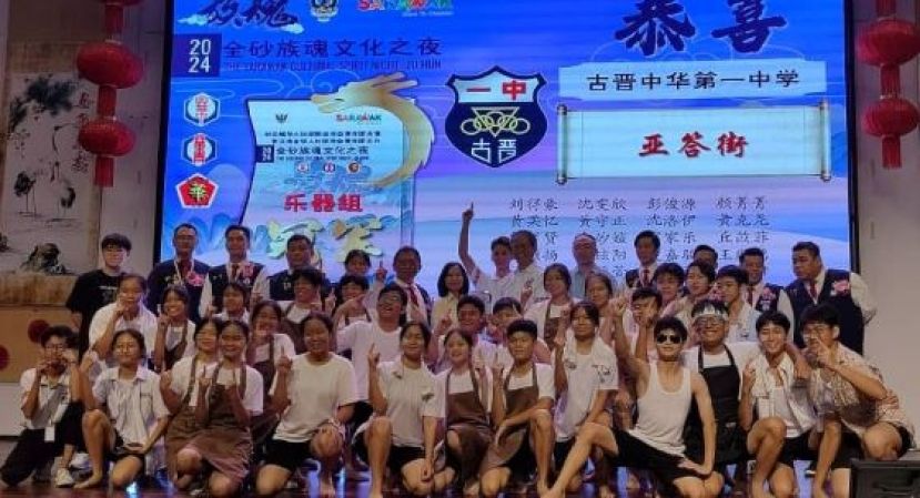 在乐器组中夺得冠军奖的古晋中华第一中学廿四节令鼓队和主宾等，在台上合影。