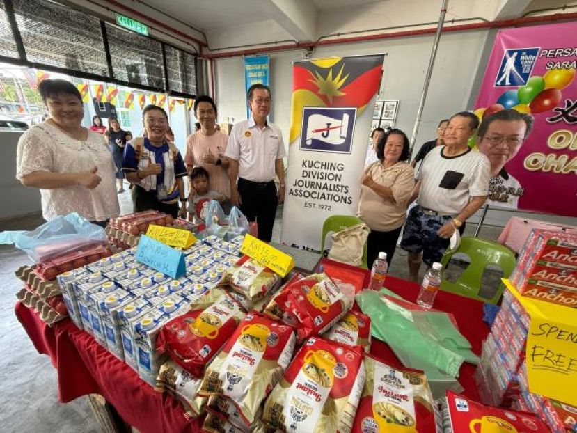 哥打圣淘沙区州议员叶耀星（左四）在古晋新闻从业员协会所设的摊位与团队成员合影留念。