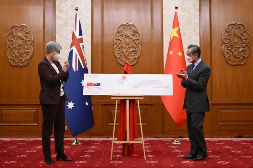 王毅（右）和黄英贤揭开中澳建交50周年纪念信封。