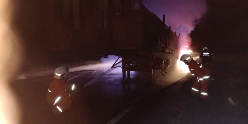 拖车后轮胎起火燃烧，消防员在灭火。