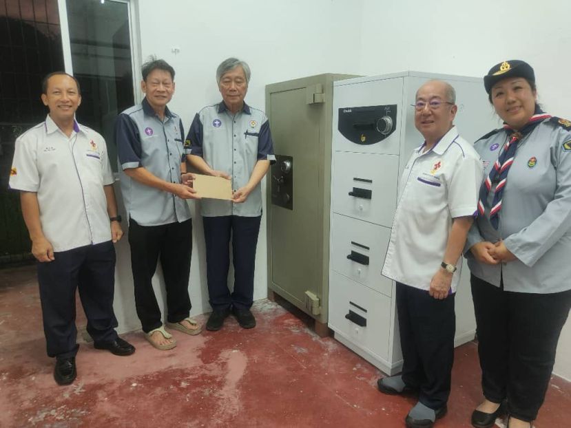 在众领袖一同见证下，古晋市童军协会会长李江胜（左二）将保险柜使用手册及钥匙移交予砂拉越童军协会执行委员会主席蔡美星，左为砂助理首席童军总监黄亚禄，右为古晋市童军协会主席张燕石与古晋市童军协会总监廖美珠。