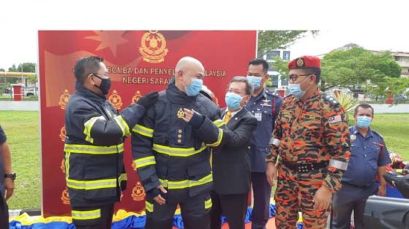 砂消拯局局长基鲁丁(左1)和拿督斯里沈桂贤(左3)共同为一名消拯局人员穿上新服饰。