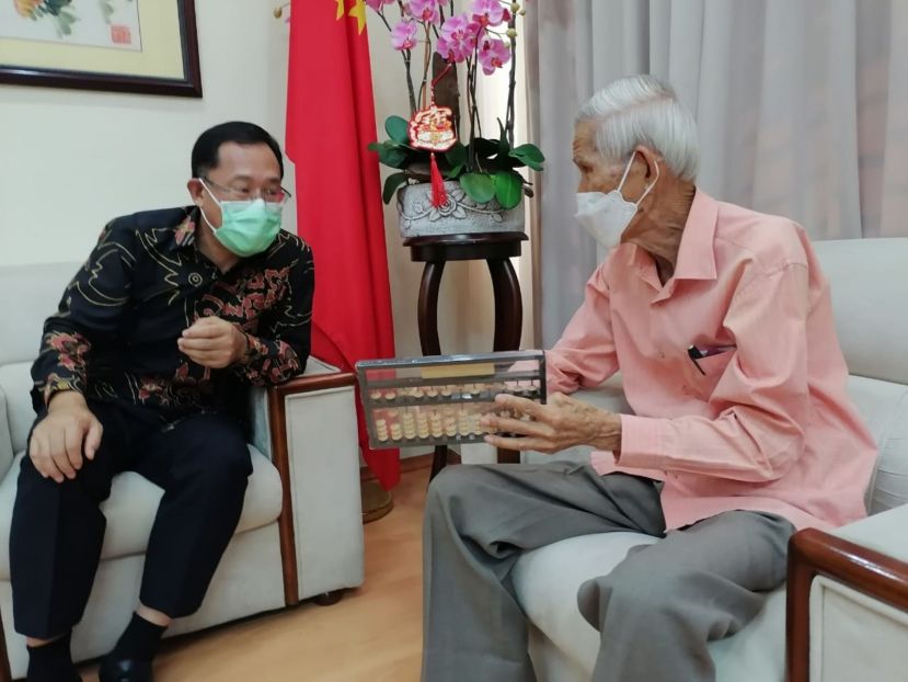邢伟平总领事（左）聆听方由传讲解其研发的方氏数字转轮算盘计算法则。