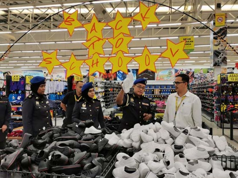 砂贸消局执法主任莫哈默哈尼占（右二）检查学生校鞋子价格。