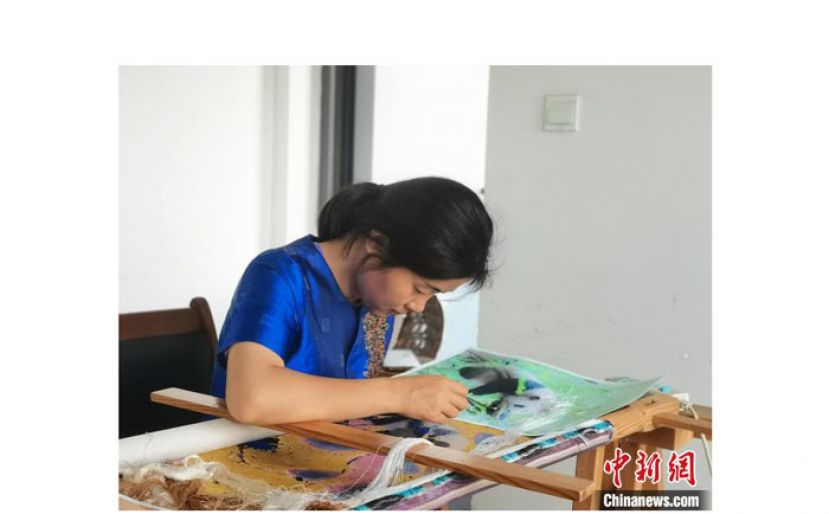 刘道华正在通过AI制图技术设计的锦绣上刺绣大熊猫。