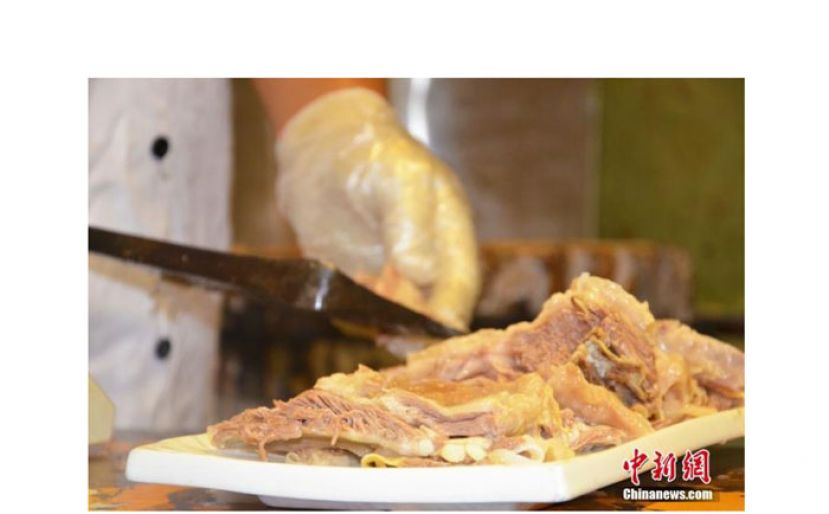 兰州主城区某手抓羊肉招牌老店内，店员正在按斤切肉。