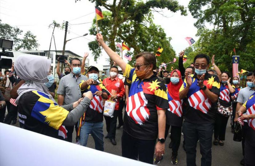 砂首长拿督巴丁宜阿邦佐哈里（中）身传辉煌条纹T恤，众人环绕成邦江展开国庆日游行。
