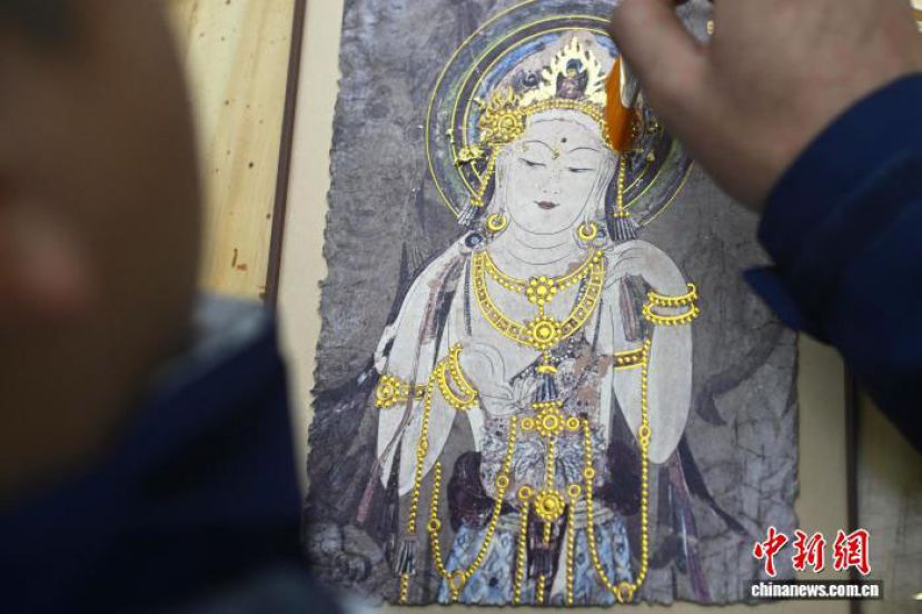 甘肃兰州城关区，&ldquo;95后&rdquo;手艺人用笔取金料，并将其附着在敦煌壁画复制品的佛像头饰上。