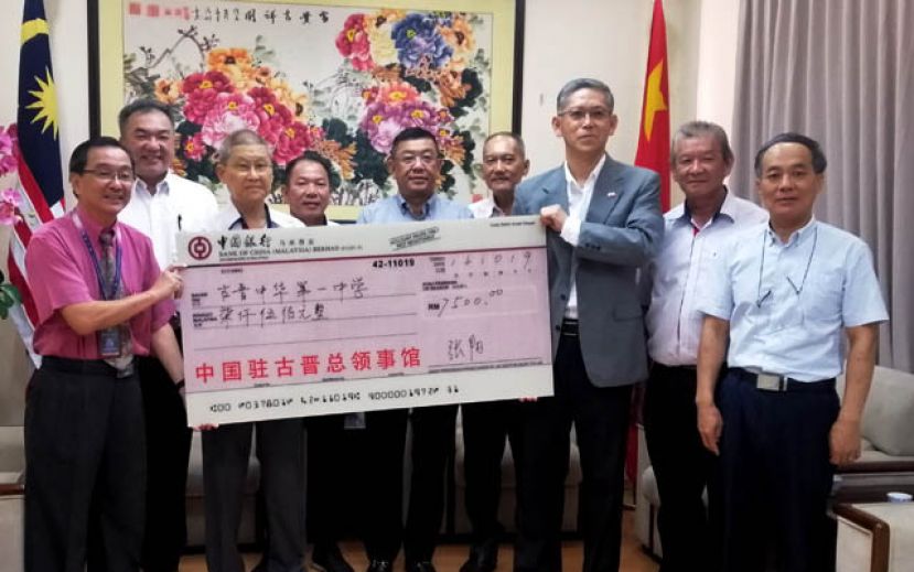 中国驻古晋总领事馆副总领事张阳（右三）移交7500令吉予中中醒狮团，由古晋一中校长叶宗元（左一）代表接收，左二起为;四中副视察何晋兴、一中助理秘书长陈健民、三中助理秘书长田玄昌、古晋中中校董会主席拿督黄良杰及四中署理主席本曼查高伟宁；右一为;程洪领事及三中视察杜亚玻。