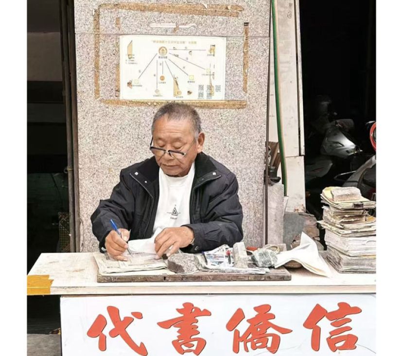 姜明典在小摊前写信。